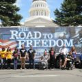 Many people, some in wheelchairs, standing in front of the ADA Legacy Bus